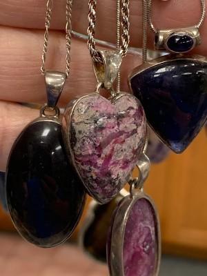 Four gemstone pendants with silver bezels on silver chains